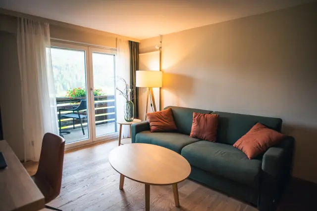 Salón de una vivienda en Asturias terminada tras una reforma integral, con tarima de madera, paredes lisas pintadas y salida a la terraza